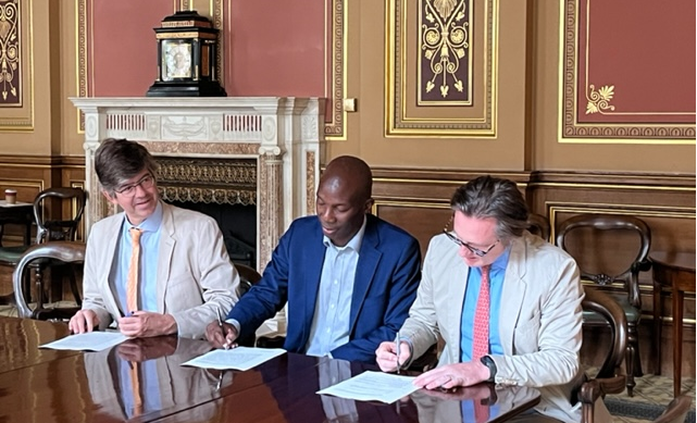 Three businessmen signing documents at official table