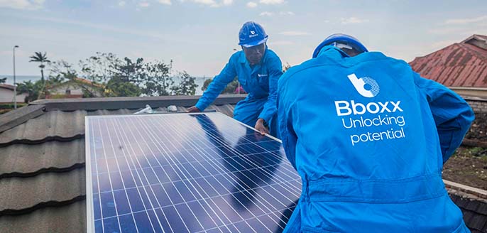 Two Engineers in PPE branded Bboxx working on solar panels